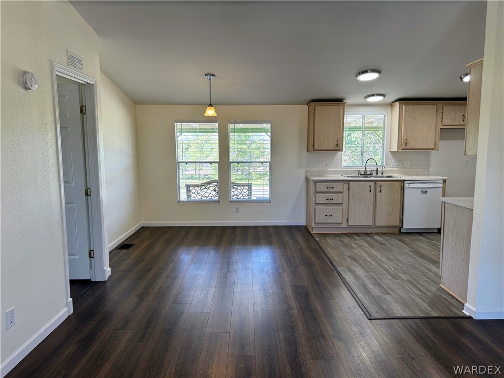 1575 South Roy Road Kingman, AZ 86401 - Photo 31 of 56 The property features an open-concept living area with dark wood-style flooring, a dining area with a pendant light fixture, and a kitchen with light wood cabinetry
