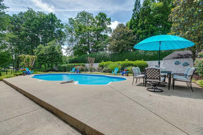 4675 Everal Lane Franklin, TN 37064 - Photo 9 of 15 a view of a swimming pool with a table and chairs under an umbrella