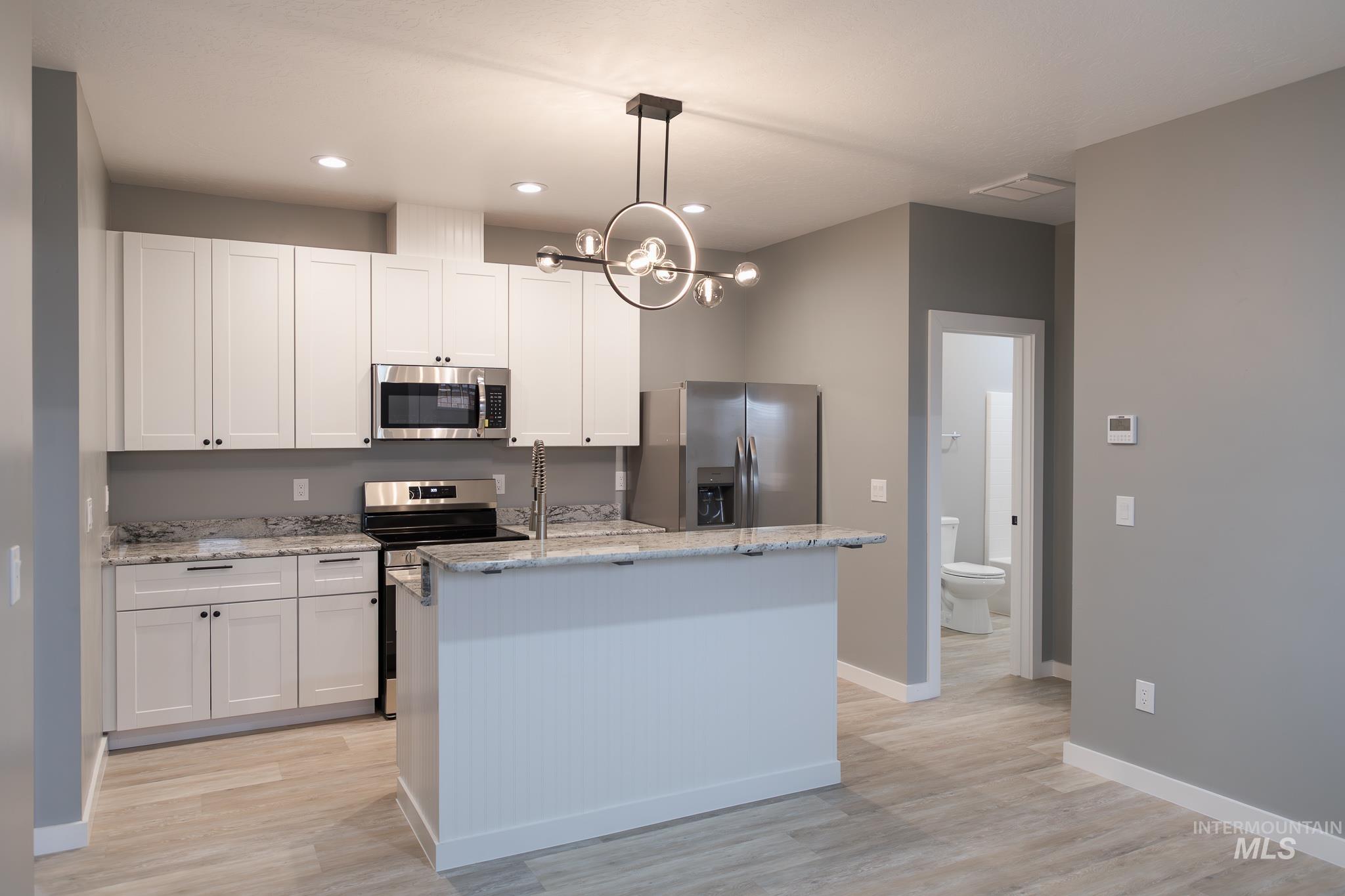 287 Southwest 6th Street, Unit 2 Ontario, OR 97914 - Photo 2 of 37 Kitchen with an island with sink, white cabinets, stainless steel appliances, and light stone counters