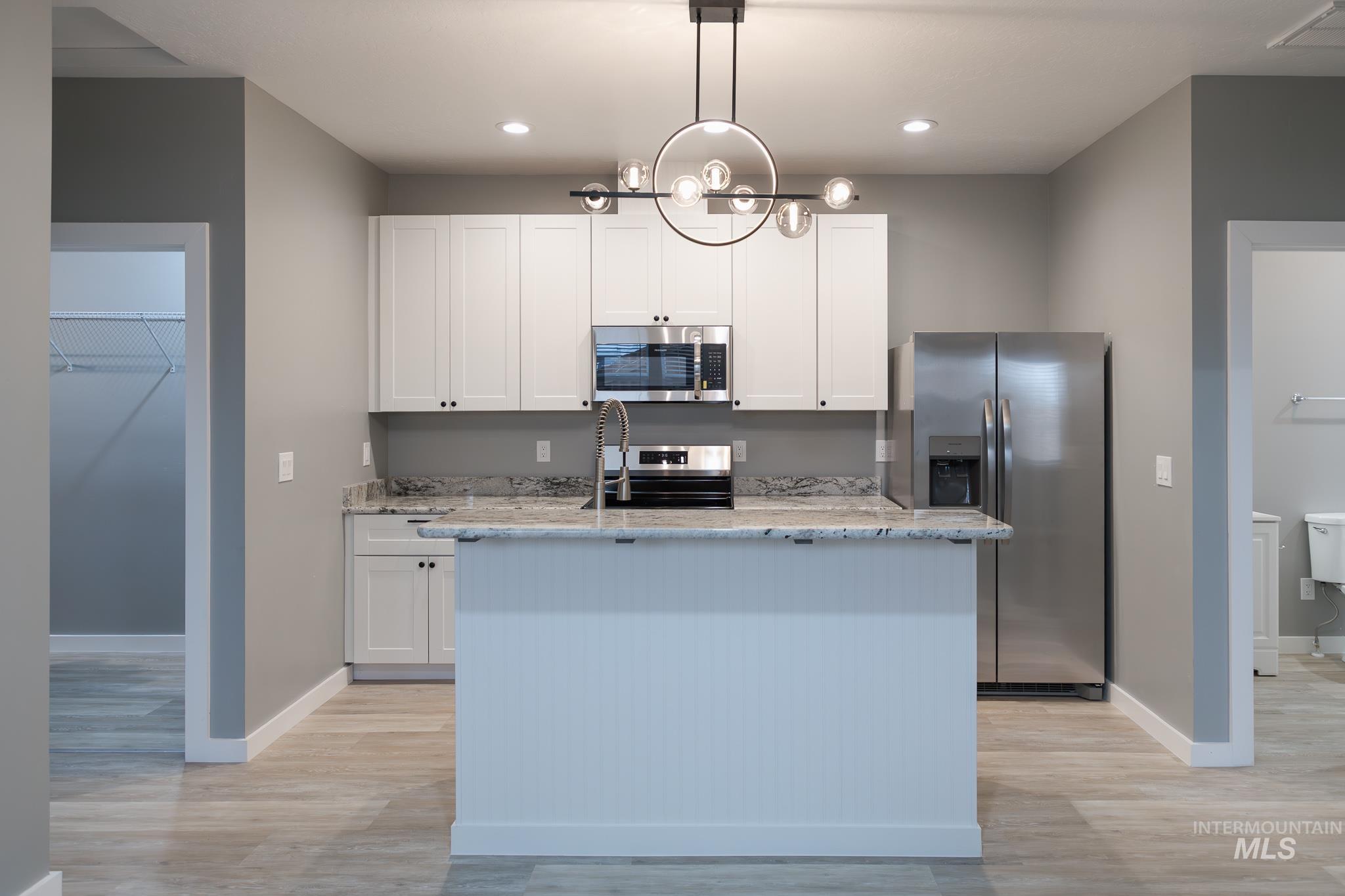 287 Southwest 6th Street, Unit 2 Ontario, OR 97914 - Photo 3 of 37 Kitchen with light stone counters, stainless steel appliances, white cabinets, an island with sink, and light wood-style flooring