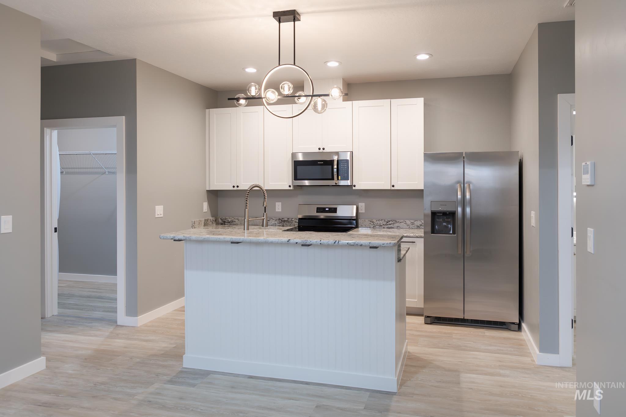 287 Southwest 6th Street, Unit 2 Ontario, OR 97914 - Photo 4 of 37 Kitchen with stainless steel appliances, light stone countertops, white cabinets, and light wood finished floors