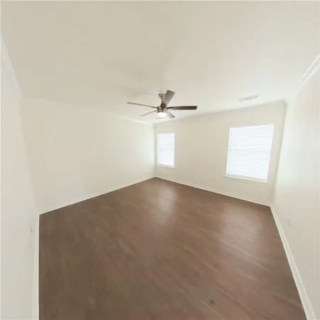 an empty room with wooden floor fan and windows