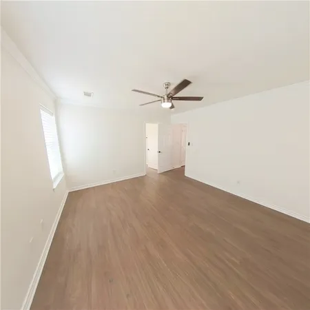 an empty room with wooden floor fan and windows