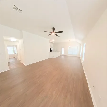 a view of a big room with wooden floor a ceiling fan and windows