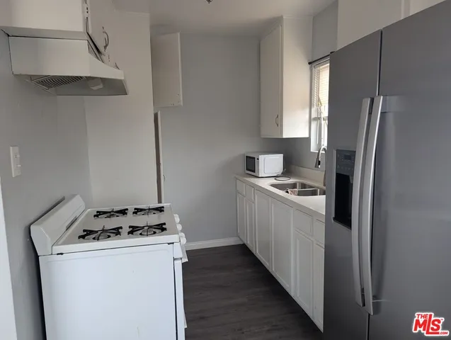 a kitchen with a refrigerator a stove and wooden floor