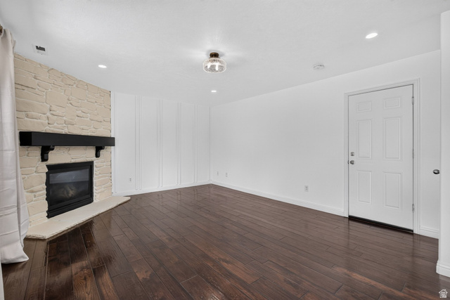 2223 North Pointe Meadow Loop Lehi, UT 84048 - Photo 18 of 56 Spacious room featuring rich wood-finish flooring, a stone-clad fireplace with a dark mantel, white wainscoting, recessed lighting, and a paneled entry door