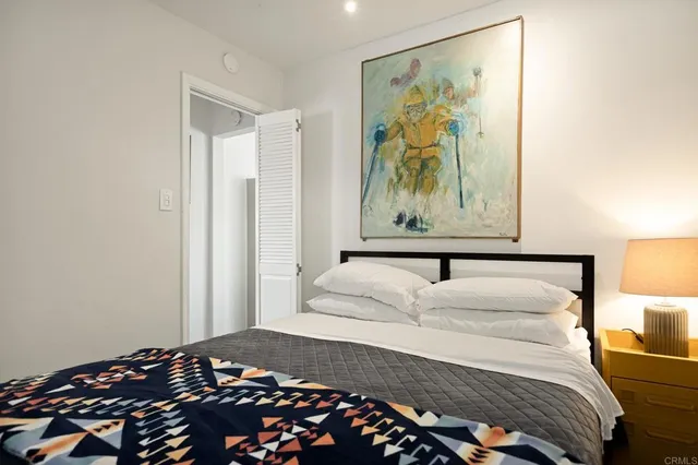 a bedroom with a large bed and a lamp on dresser