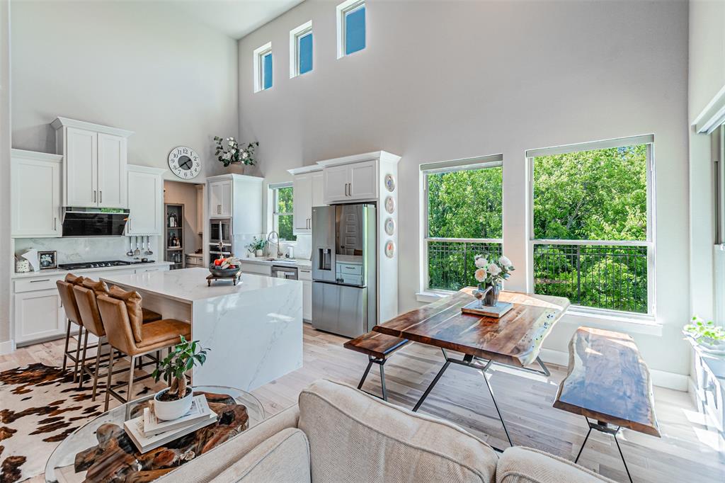 1070 Adair Road Prosper, TX 75078 - Photo 15 of 40 Vaulted ceilings amplify this open-concept space featuring a gourmet kitchen with white shaker cabinetry, a waterfall island with stone countertops, and stainless steel appliances