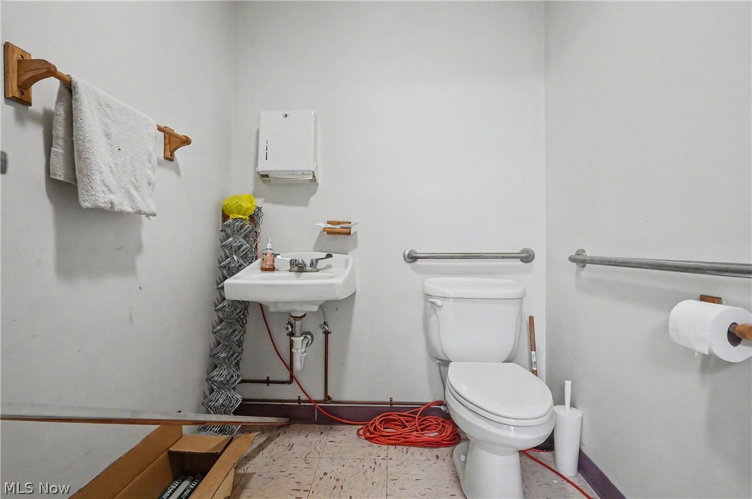 4250 Herr Fieldhouse Road Southington, OH 44470 - Photo 35 of 50 Restroom featuring a wall-mounted sink, toilet, and multiple grab bars