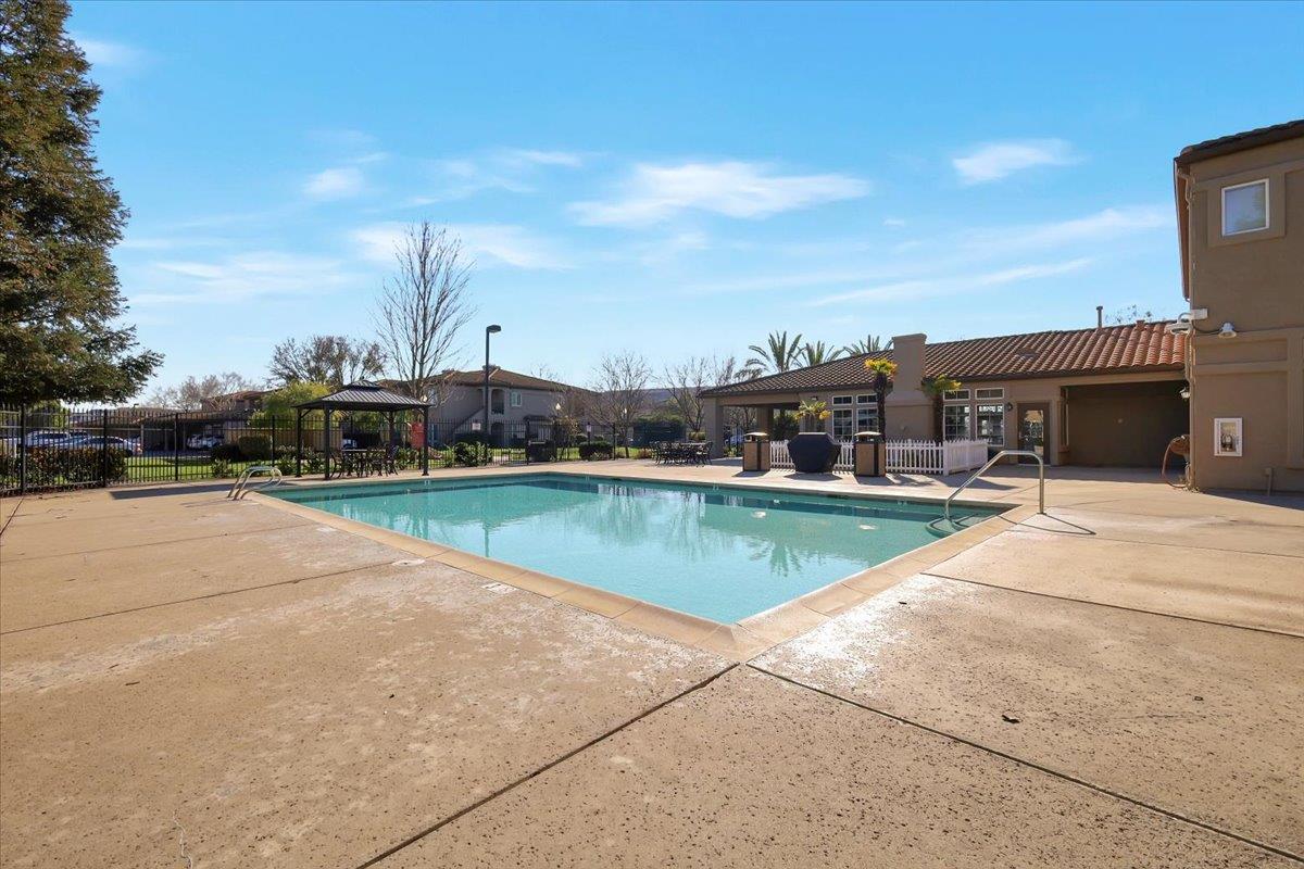 4200 East Commerce, Unit 1121 Sacramento, CA 95834 - Photo 21 of 24 a view of swimming pool that has lawn chairs and a dining table under an umbrella
