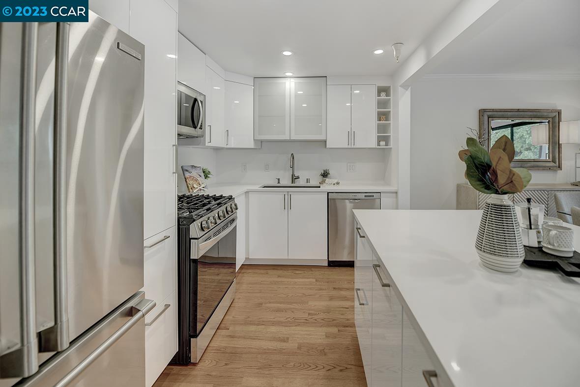 a kitchen with stainless steel appliances granite countertop a refrigerator a sink a stove and white cabinets