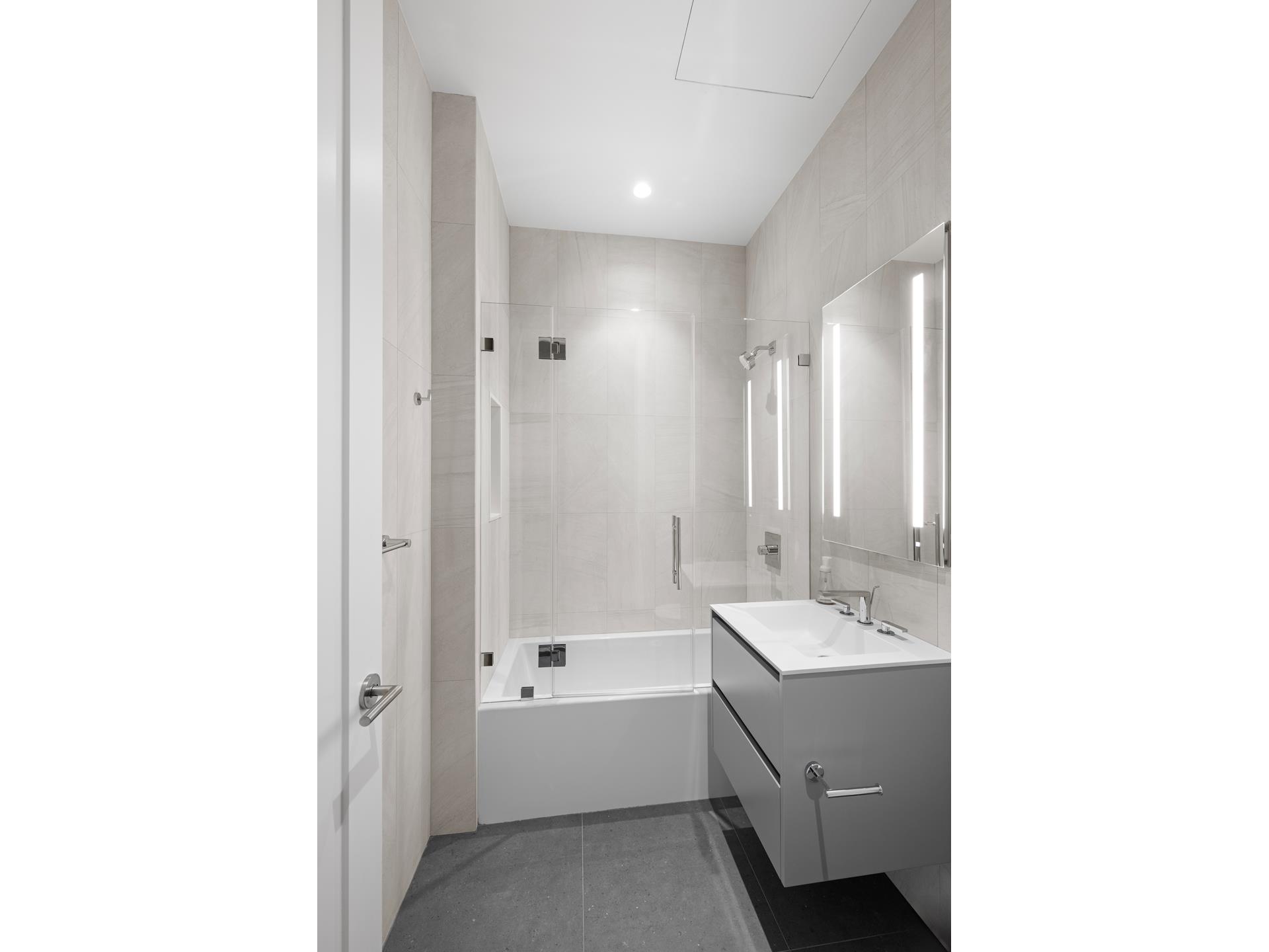 290 West Street, Unit 2B Manhattan, NY 10013 - Photo 12 of 14 a bathroom with a double vanity sink a mirror and a bathtub