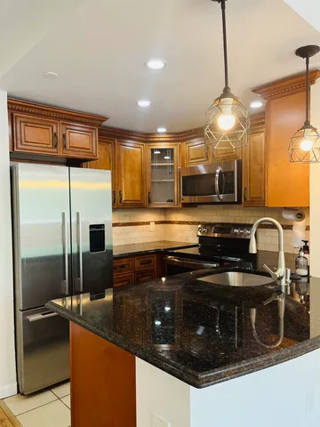 a kitchen with stainless steel appliances granite countertop a sink a stove and a refrigerator