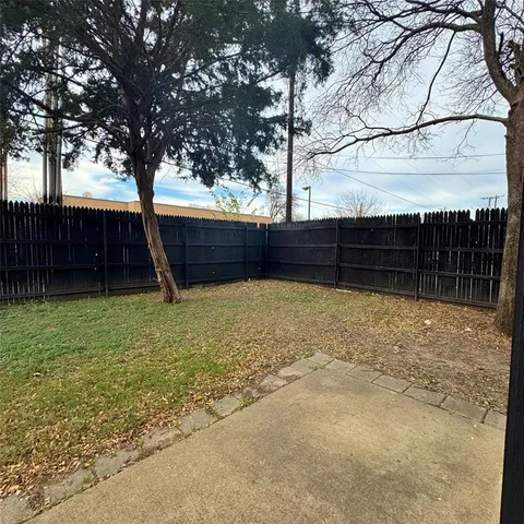 a view of backyard with wooden fence and a large tree