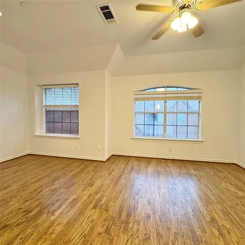 an empty room with wooden floor chandelier and windows