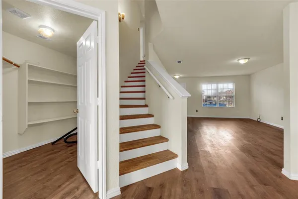 a view of a hallway with wooden floor and stairs