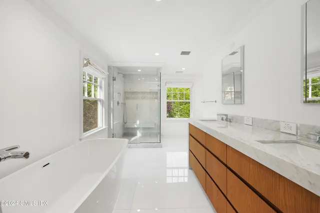 a spacious bathroom with a tub sink and mirror