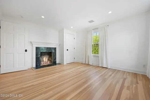a view of empty room with wooden floor and fireplace