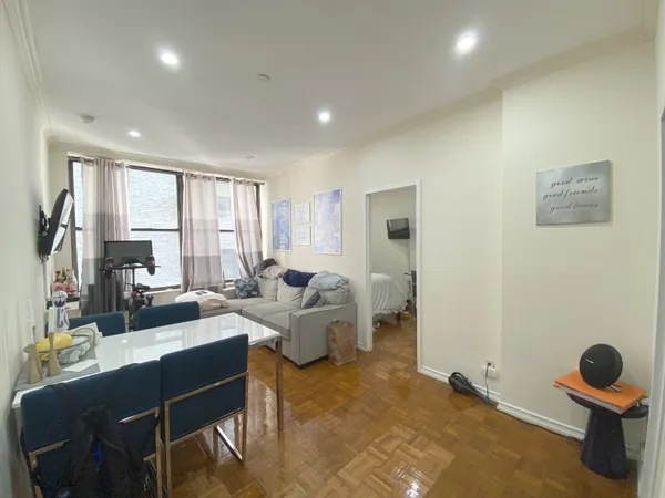 a living room with couches chairs and dresser with wooden floor