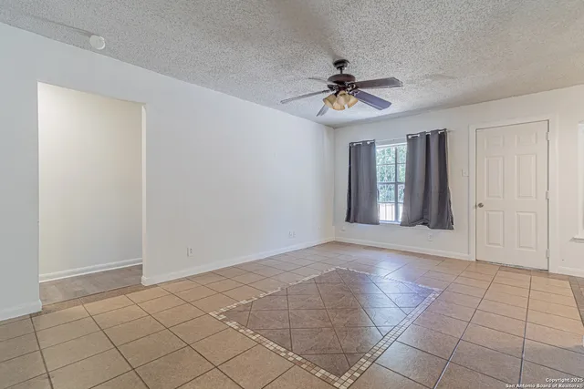 a view of an empty room with window and chandelier fan