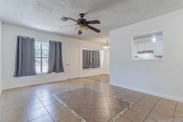a view of an empty room with window and chandelier fan