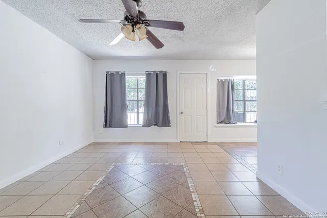 a view of an empty room with window and chandelier fan