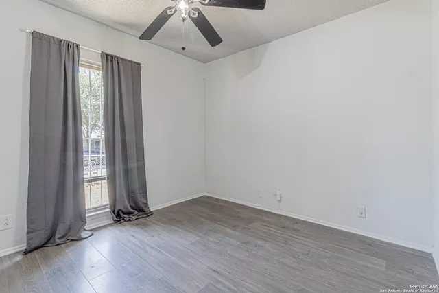 an empty room with wooden floor and windows