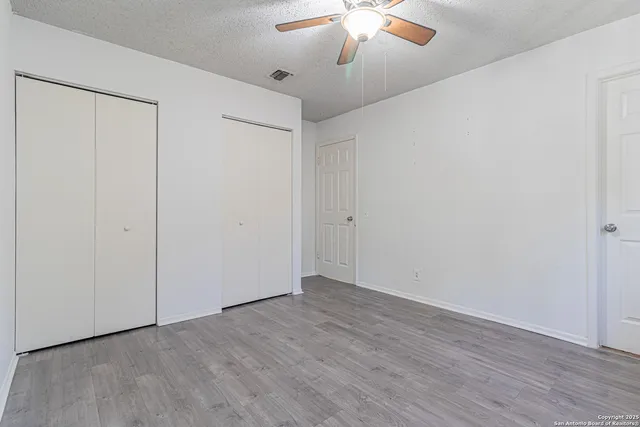 an empty room with wooden floor chandelier fan and closet area