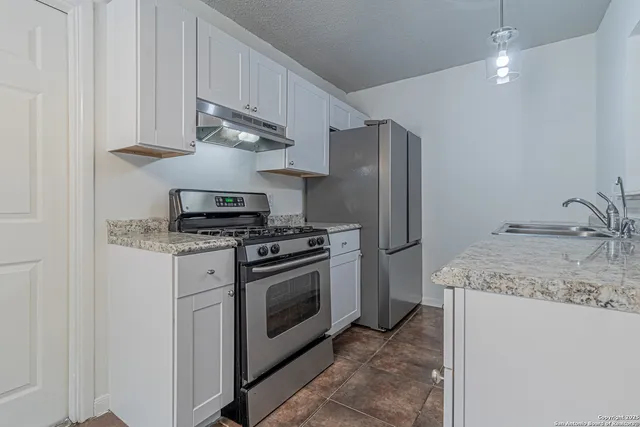 a kitchen with stainless steel appliances granite countertop a refrigerator sink and stove