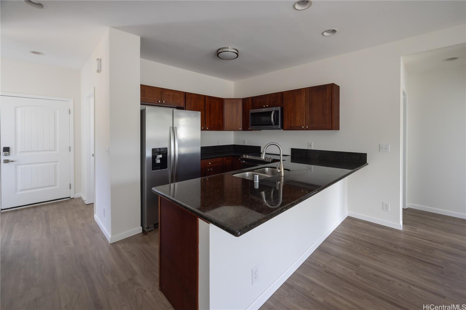 87-176 Maipalaoa Road, Unit Q38 Waianae, HI 96792 - Photo 5 of 18 a kitchen with stainless steel appliances a sink a microwave a refrigerator and wooden floor