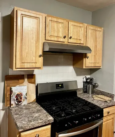 a kitchen with granite countertop a stove and a white cabinets