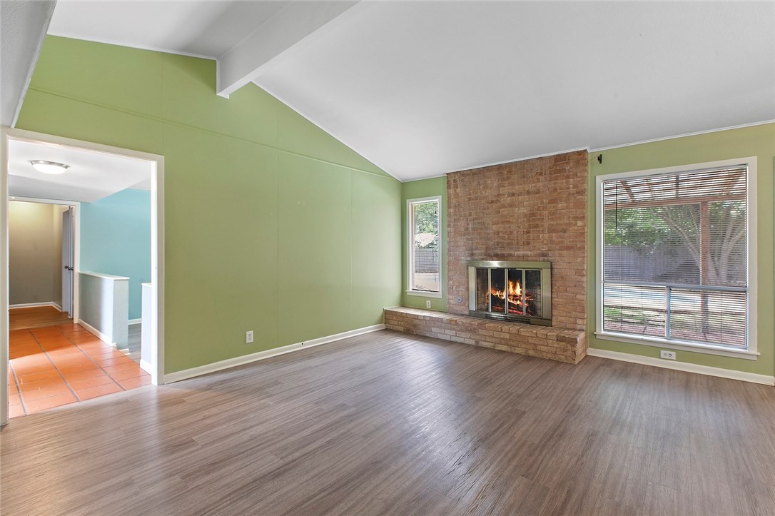 a view of an empty room with wooden floor a fireplace