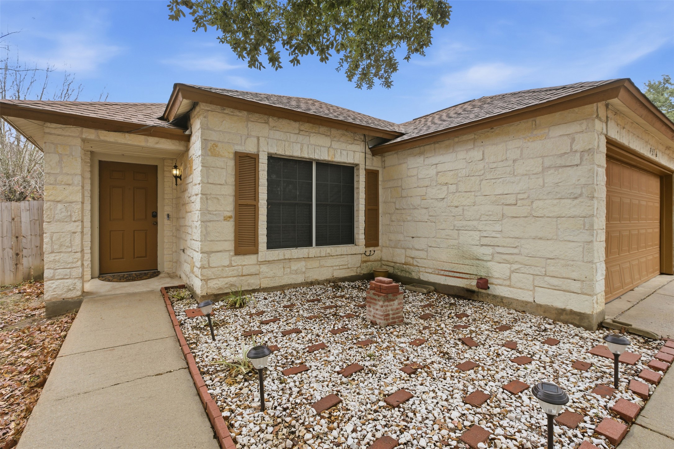 7536 Marble Ridge Drive Austin, TX 78747 - Photo 8 of 30 Doorway to property featuring stone siding, an attached garage, and roof with shingles