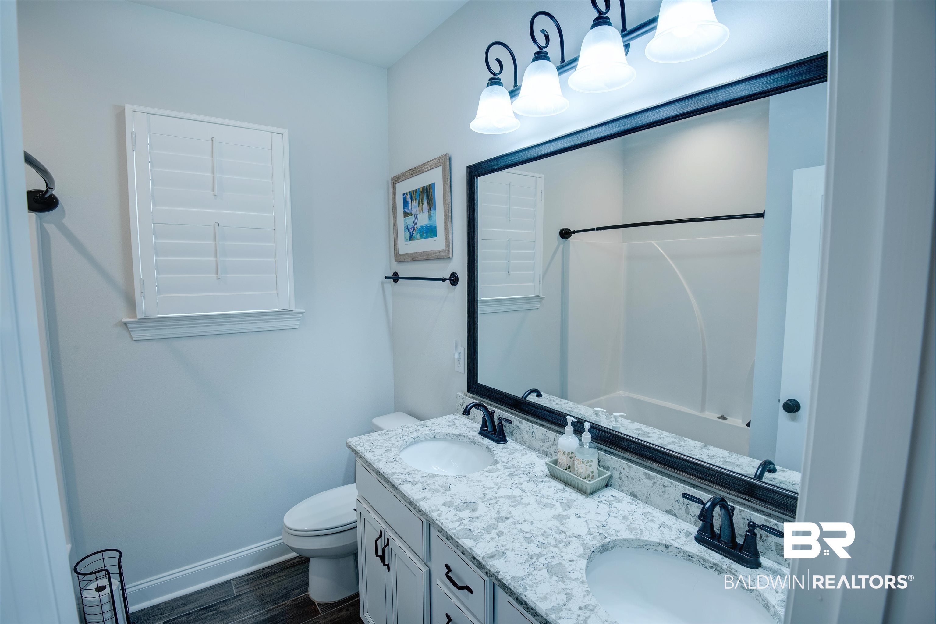 9843 Chipper Lane Foley, AL 36535 - Photo 22 of 34 Bathroom with baseboards, double vanity, shower / washtub combination, toilet, and wood finished floors