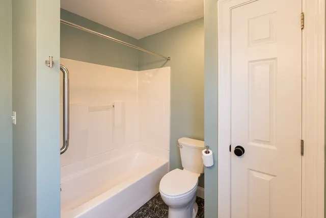 a bathroom with a granite countertop bathtub shower and toilet
