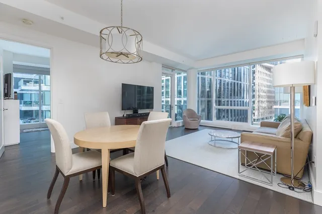 a dining room with wooden floor a chandelier a glass table and chairs