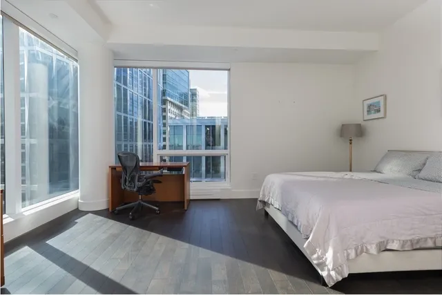 a bedroom with a bed and large windows