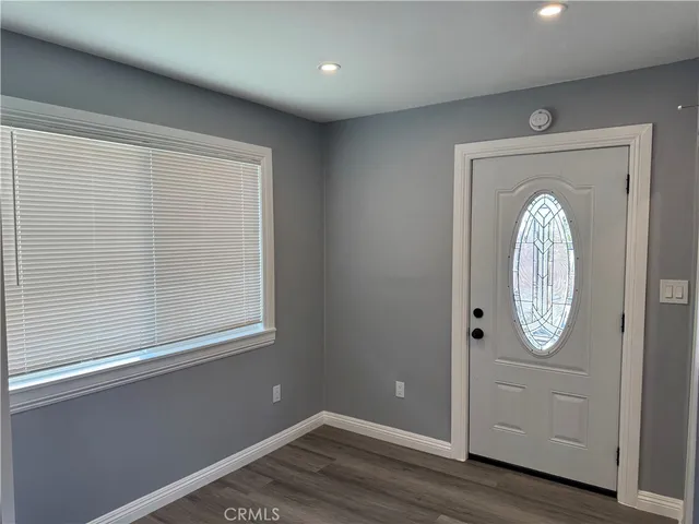 an empty room with wooden floor cabinet and mirror