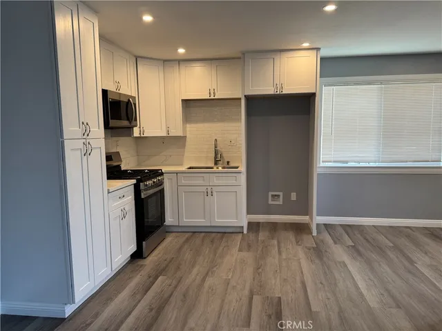 a kitchen with a refrigerator a stove top oven a sink and dishwasher with wooden floor