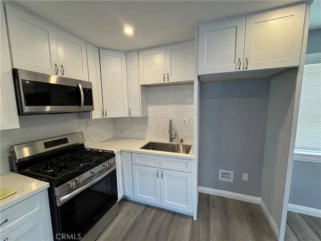a kitchen with granite countertop a stove and a wooden floor
