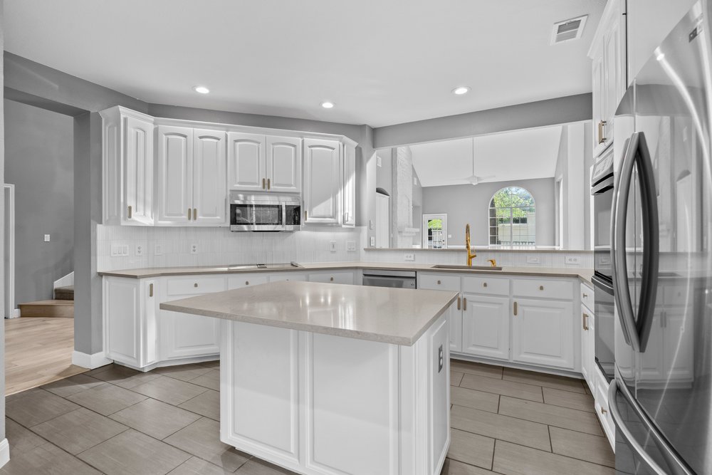 1815 Rue De St Tropez Austin, TX 78746 - Photo 25 of 40 Kitchen featuring white cabinetry, light-toned countertops, stainless steel appliances, and tile flooring