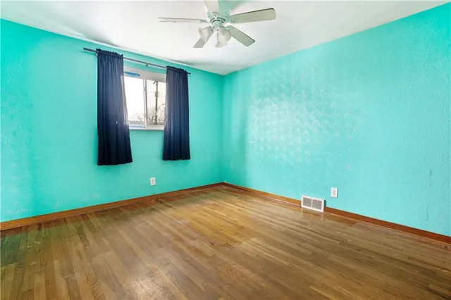 a view of an empty room with window and wooden floor