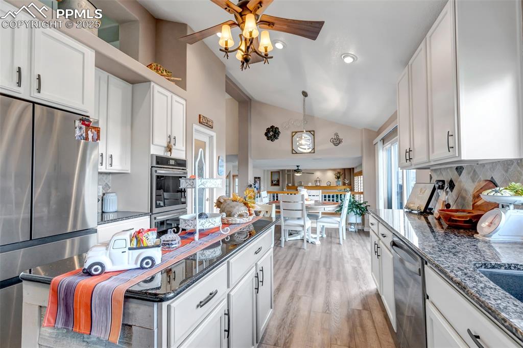 7120 Highcroft Drive Colorado Springs, CO 80922 - Photo 14 of 50 a kitchen with stainless steel appliances granite countertop a refrigerator a sink dishwasher a stove and a dining table with wooden floor