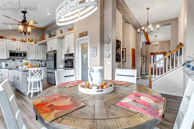a dining room with wooden floor a chandelier a wooden table and chairs