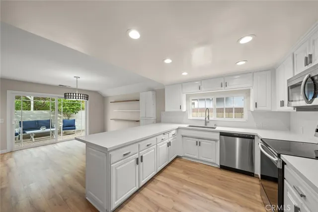 a kitchen with white cabinets and wooden floors