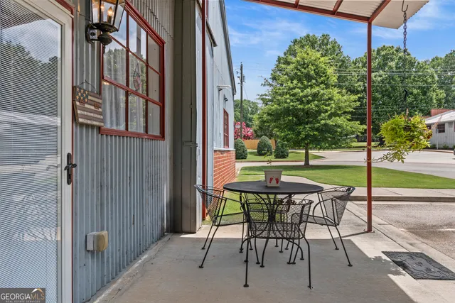 a patio with table and chairs and potted plants