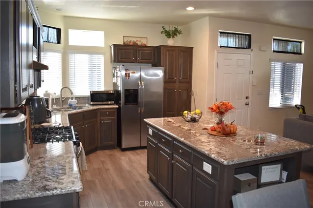 a kitchen with granite countertop kitchen island stainless steel appliances a sink stove and refrigerator