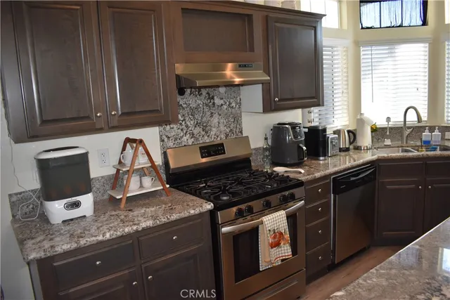 a kitchen with stainless steel appliances granite countertop a sink stove and cabinets
