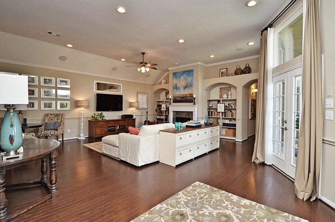 1447 Ralston Branch Way Sugar Land, TX 77479 - Photo 4 of 21 Further in, the living room invites you to relax under warm lighting, surrounded by touches of refinement, from crown molding and artful wall niches to the double French doors leading out to the patio. Broad windows filter in sunlight that dances across the glossy floors.