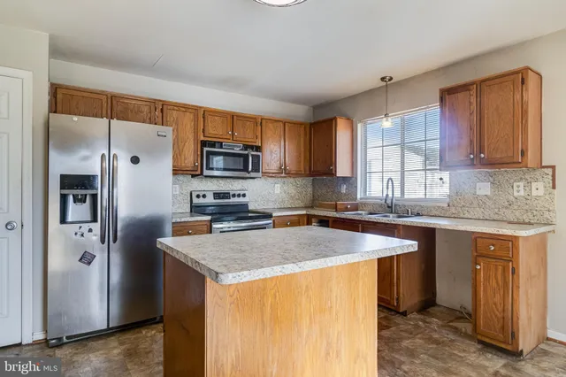 a kitchen with stainless steel appliances granite countertop a refrigerator a sink a stove a microwave and island